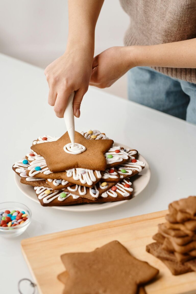 Hands decorating star-shaped cookies with icing for Christmas.